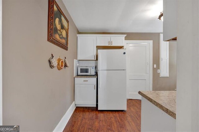 kitchen with decorative backsplash, white appliances, white cabinets, and dark hardwood / wood-style floors