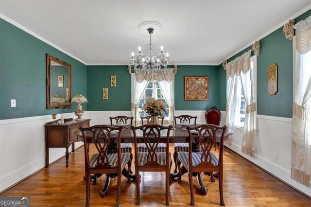 dining room featuring a chandelier, a wealth of natural light, hardwood / wood-style floors, and ornamental molding