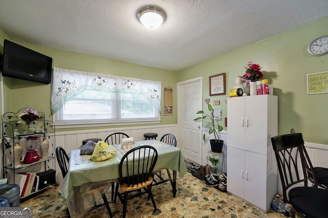 dining room featuring a textured ceiling and wooden walls