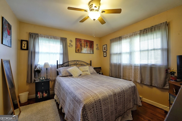 bedroom featuring dark wood-type flooring, multiple windows, and ceiling fan