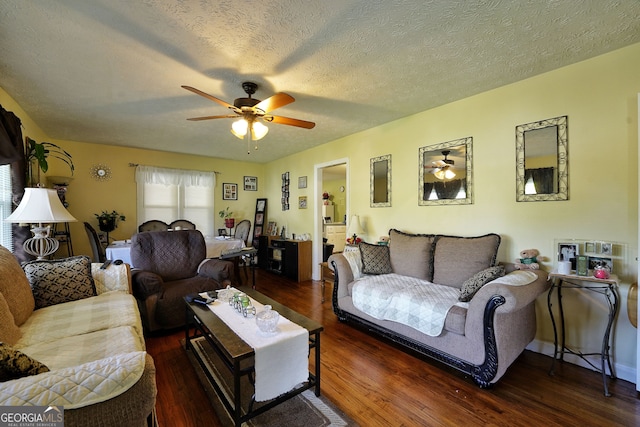 living room with a textured ceiling, dark hardwood / wood-style floors, and ceiling fan