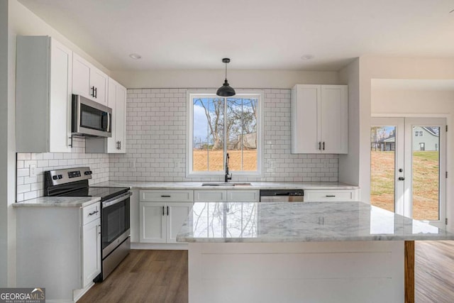 kitchen with pendant lighting, stainless steel appliances, white cabinets, and sink