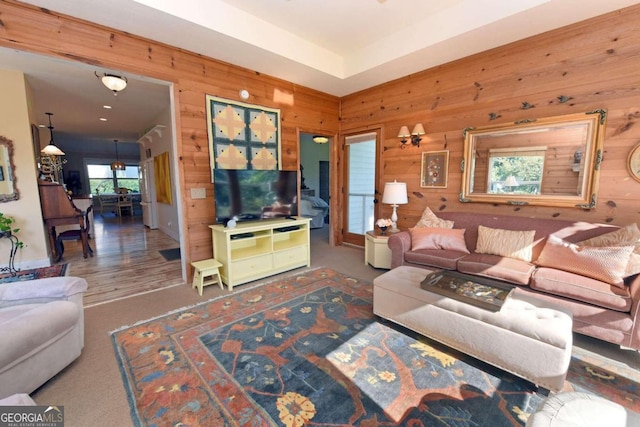 living room featuring ceiling fan, wood walls, and wood-type flooring