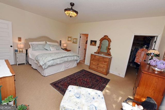 bedroom featuring a walk in closet, light carpet, and a closet