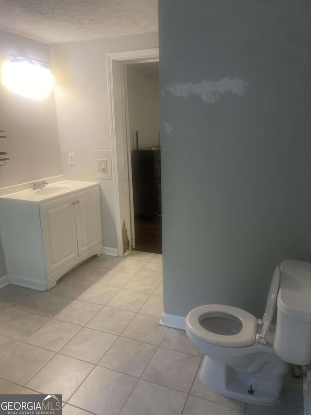 bathroom featuring vanity, tile patterned flooring, toilet, and a textured ceiling