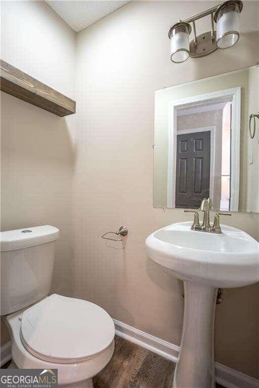 bathroom featuring toilet, wood-type flooring, and sink