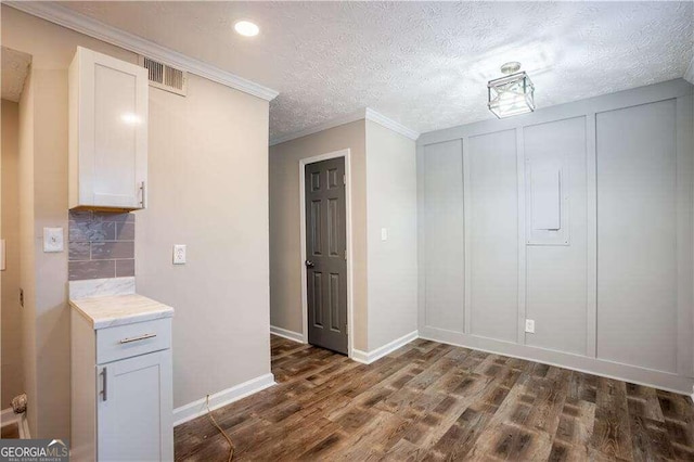 interior space with a textured ceiling, dark hardwood / wood-style flooring, and ornamental molding