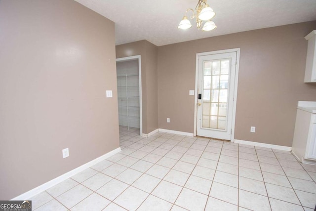 unfurnished dining area with a chandelier, a textured ceiling, and light tile patterned floors