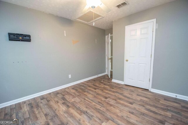 unfurnished bedroom with a textured ceiling and dark wood-type flooring