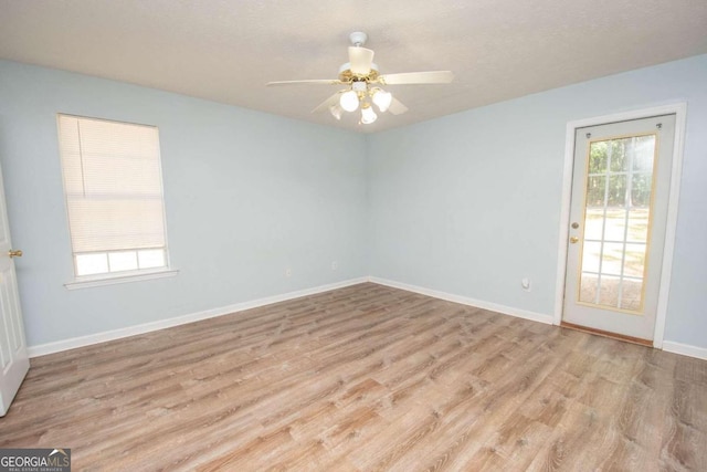 empty room featuring a healthy amount of sunlight, light hardwood / wood-style floors, and ceiling fan