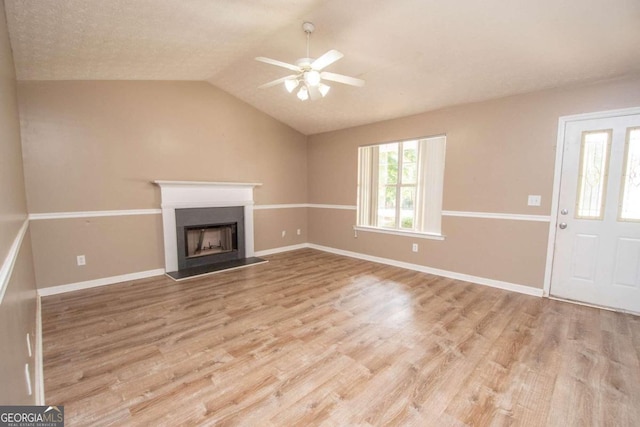 unfurnished living room with light hardwood / wood-style flooring, lofted ceiling, ceiling fan, and a textured ceiling