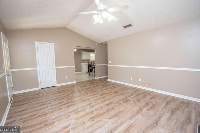 interior space with light wood-type flooring, a textured ceiling, lofted ceiling, and ceiling fan