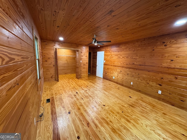 empty room with ceiling fan, wooden walls, light hardwood / wood-style floors, and wooden ceiling