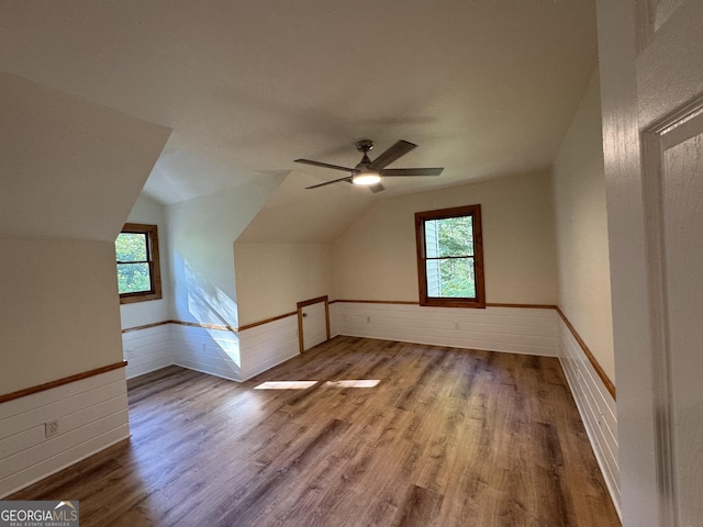 bonus room featuring lofted ceiling, wainscoting, wooden walls, and wood finished floors