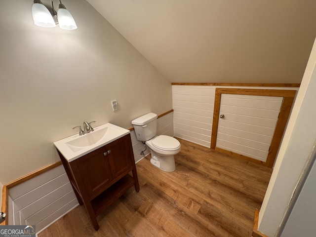 bathroom featuring vanity, hardwood / wood-style flooring, lofted ceiling, and toilet