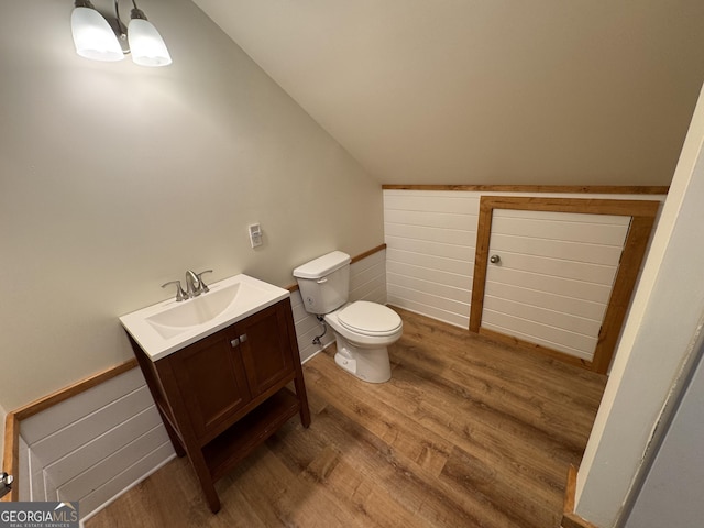 bathroom with lofted ceiling, vanity, toilet, and wood finished floors