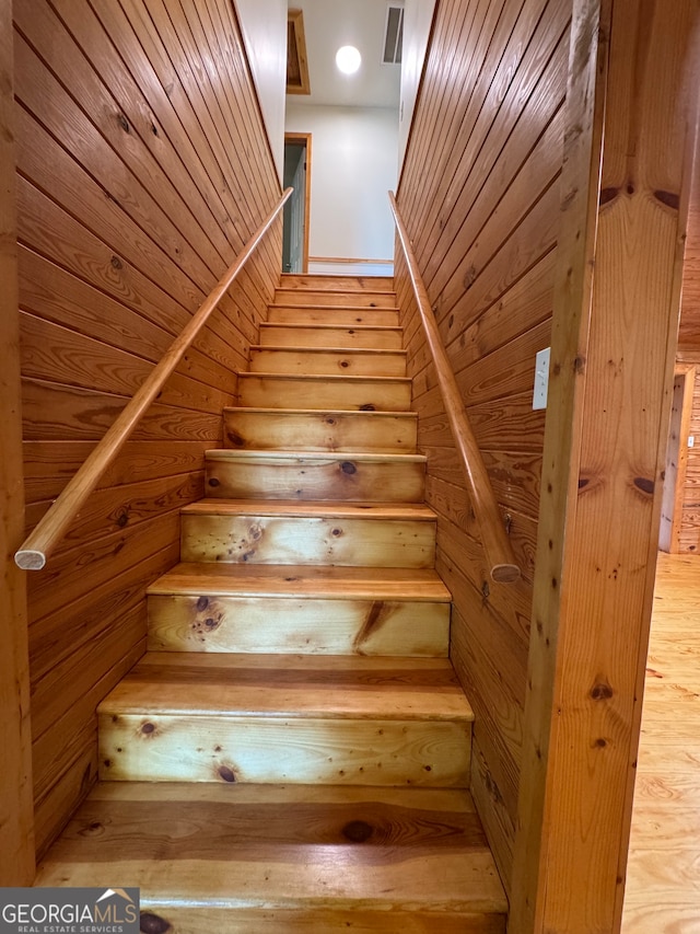 staircase with wood walls and hardwood / wood-style flooring