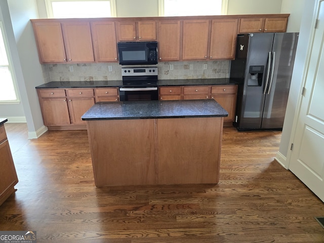 kitchen featuring a kitchen island, dark wood-type flooring, appliances with stainless steel finishes, and tasteful backsplash