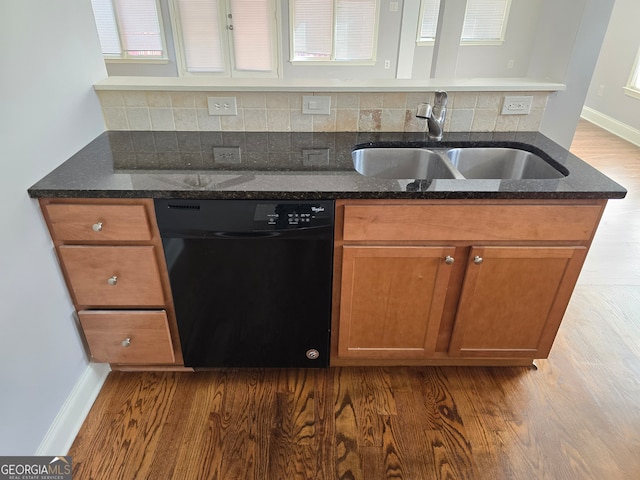 kitchen with decorative backsplash, dark stone countertops, dishwasher, hardwood / wood-style floors, and sink