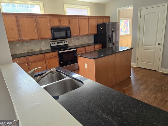 kitchen featuring sink, a kitchen island, stainless steel appliances, dark hardwood / wood-style flooring, and decorative backsplash