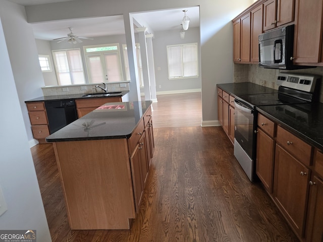 kitchen with dark wood-type flooring, tasteful backsplash, a kitchen island, black appliances, and ceiling fan