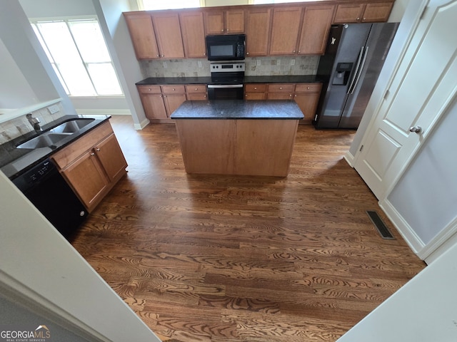 kitchen featuring sink, a kitchen island, decorative backsplash, black appliances, and dark hardwood / wood-style flooring