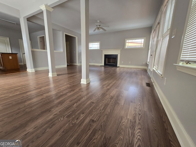 unfurnished living room featuring ceiling fan, ornate columns, and dark hardwood / wood-style flooring