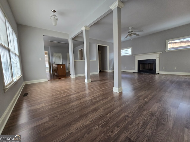 unfurnished living room featuring ceiling fan, dark hardwood / wood-style floors, and ornate columns