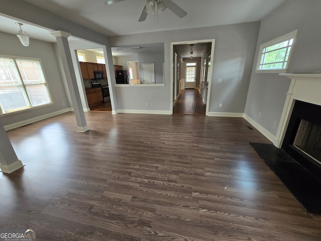 unfurnished living room featuring ceiling fan, dark hardwood / wood-style floors, and ornate columns