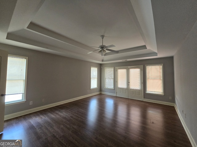 spare room featuring a tray ceiling, dark hardwood / wood-style floors, ceiling fan, and french doors