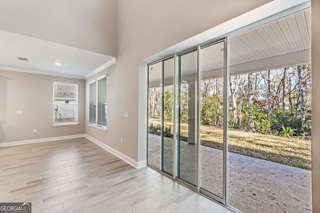 entryway with a healthy amount of sunlight, ornamental molding, and light hardwood / wood-style floors