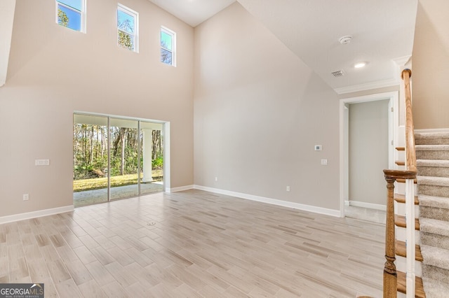 unfurnished living room featuring a high ceiling, plenty of natural light, and light hardwood / wood-style floors