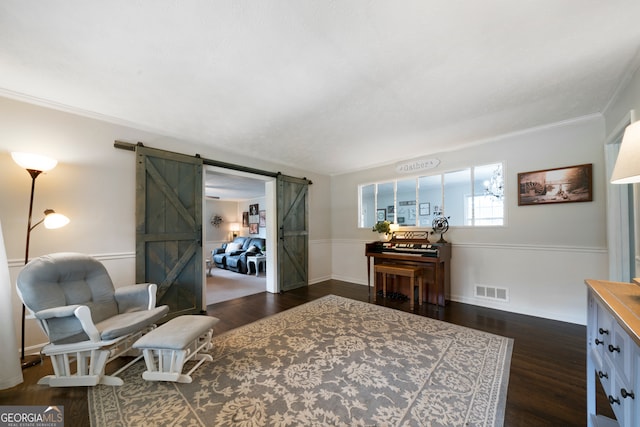 living area featuring ornamental molding, dark hardwood / wood-style floors, and a barn door