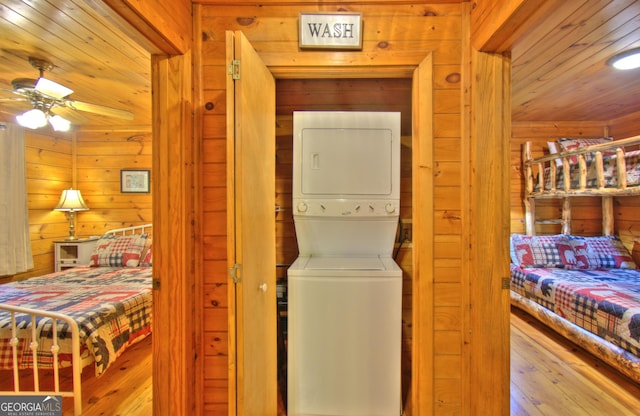 laundry room featuring light hardwood / wood-style floors, ceiling fan, and stacked washer and clothes dryer