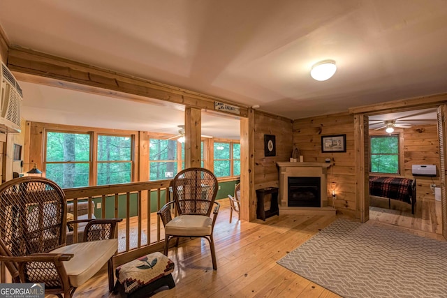 living room featuring ceiling fan, wood walls, and light hardwood / wood-style flooring