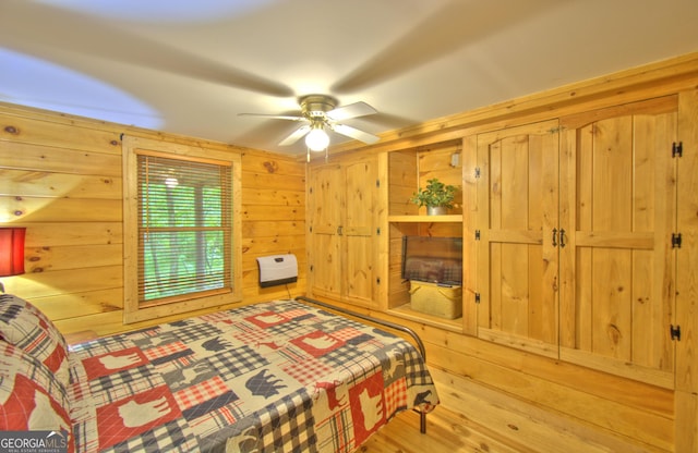 bedroom featuring ceiling fan and wooden walls