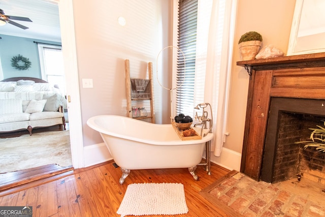 1651 Mergendollar Rd, Good Hope, GA 30641 - ensuite bathroom featuring baseboards, a freestanding bath, a ceiling fan, a fireplace, and wood finished floors
