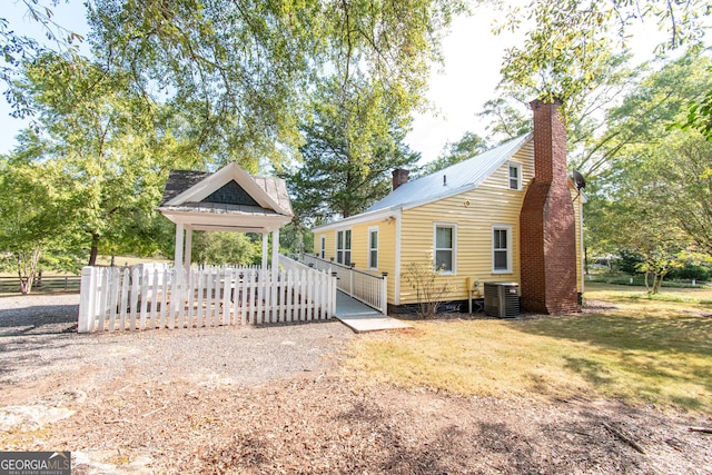 1651 Mergendollar Rd, Good Hope, GA 30641 - view of home's exterior with central AC, a lawn, metal roof, fence, and a chimney
