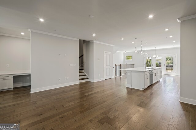 unfurnished living room with ornamental molding, dark hardwood / wood-style floors, a chandelier, and sink