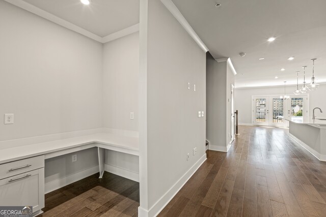 hallway featuring a chandelier, dark hardwood / wood-style floors, and crown molding