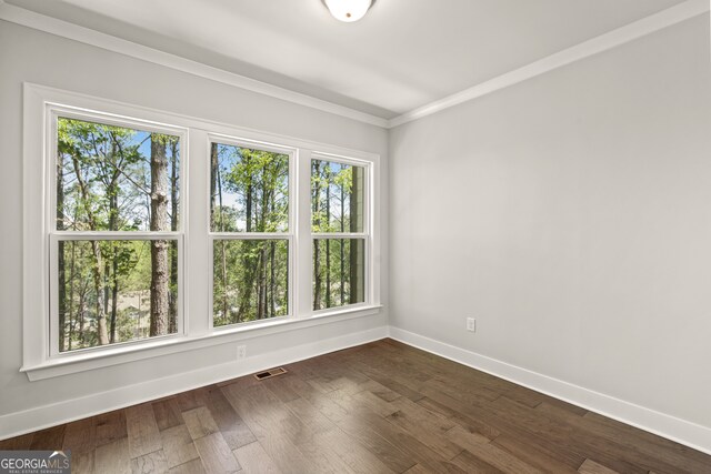 empty room featuring dark hardwood / wood-style floors, crown molding, and a wealth of natural light