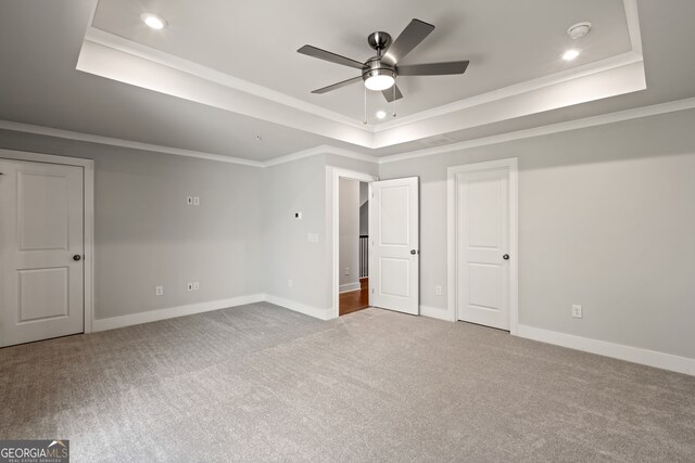 unfurnished bedroom featuring light carpet, a tray ceiling, and ceiling fan