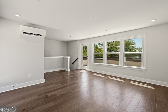 empty room with dark wood-type flooring and a wall mounted AC