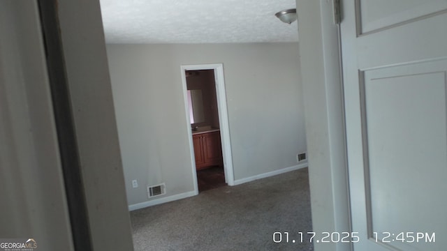 empty room with a textured ceiling and carpet flooring