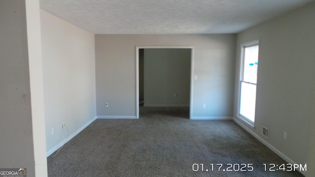 spare room with a healthy amount of sunlight, a textured ceiling, and carpet flooring