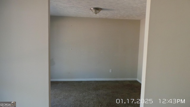 empty room featuring a textured ceiling and dark colored carpet