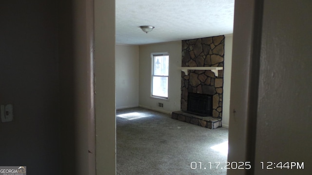 unfurnished living room featuring carpet floors, a textured ceiling, and a fireplace