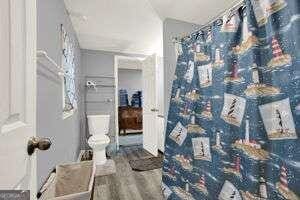 bathroom featuring wood-type flooring, curtained shower, and toilet