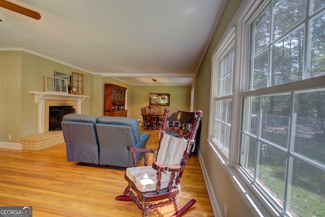 living room featuring light hardwood / wood-style flooring, a brick fireplace, ceiling fan, and ornamental molding