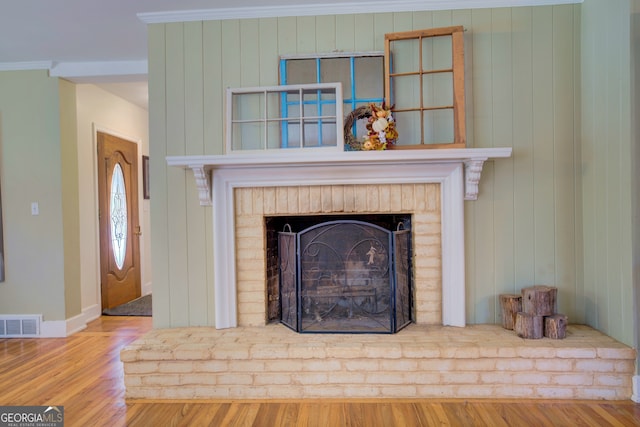 room details with wooden walls, a fireplace, crown molding, and hardwood / wood-style floors